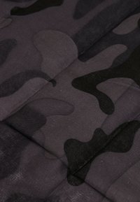 Black and gray camouflage fabric with a soft texture, featuring irregular patches and smooth seams, suitable for clothing or accessories.