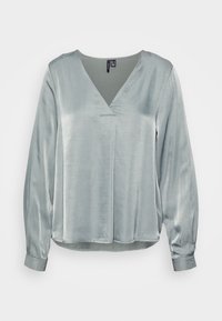 Blusa de cetim azul claro com mangas longas, decote em V profundo e corte reto. Textura suave com detalhe de costura mínimo.