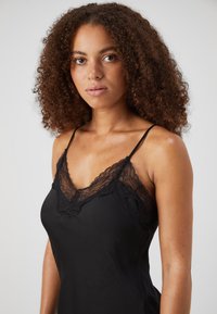 Black satin nightgown with lace trim along the neckline and straps. Features a fitted design and soft texture, with a smooth finish.