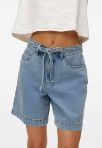 Šviesiai mėlynos džinsinės šortai su laisvu siluetu, raišteliu talijoje, priekiniu kišeniu ir sulenkta apdaila. Slypi audinio tekstūra su lengvu nusidėvėjimu.