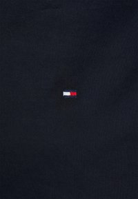 Tessuto blu navy con un piccolo logo ricamato che presenta un rettangolo orizzontale rosso, bianco e blu al centro. Design semplice e pulito.