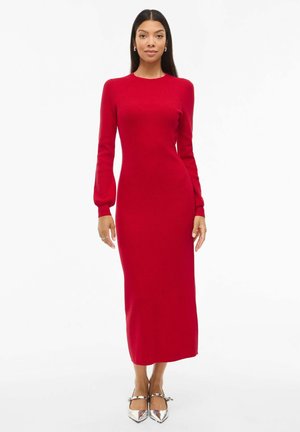 Abito midi lavorato a maglia rosso con maniche lunghe, silhouette aderente, scollo rotondo e tessuto liscio. Abbinato a scarpe argentate con punta a mandorla.
