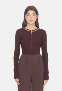 Maglione a maglia bordeaux con un motivo testurizzato, scollo rotondo e zip dorata. Presenta maniche lunghe e una silhouette aderente.