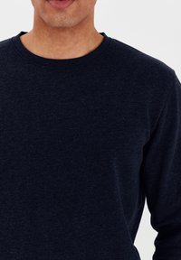 Marineblauwe longsleeve crewneck sweatshirt gemaakt van een zachte, gestructureerde stof met een klassieke pasvorm en geribde halslijn.