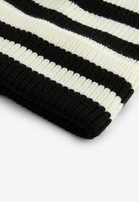 Schwarz-weiß gestreifter Strickstoff mit gerippter Textur, der breite horizontale Streifen und eine gefaltete Kante aufweist.