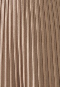 Tessuto plissettato in un morbido colore beige, caratterizzato da strisce verticali che creano una superficie testurizzata. Il materiale appare leggero e morbido.