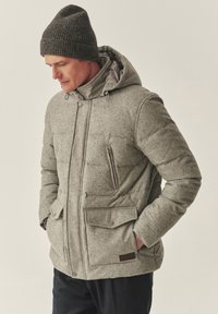 Szara pikowana kurtka z kapturem, przednim zamkiem błyskawicznym i zapięciami na zatrzaski. Ciemnoszara prążkowana czapka oraz teksturowana tkanina dla izolacji termicznej.