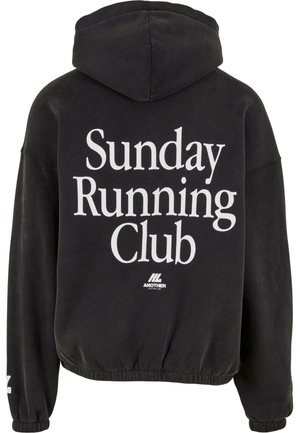 Felpa nera con la scritta "Sunday Running Club" in grandi lettere bianche sul retro e un piccolo logo "Another Cotton Lab" sottostante.