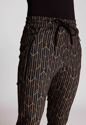Schwarze Hosen mit einem geometrischen beigen Muster, elastischem Bund mit Kordelzug und seitlichen Reißverschlusstaschen für zusätzliches Feinteresse.