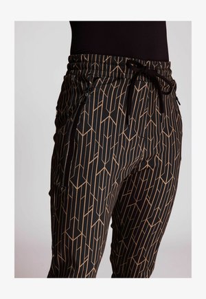 Schwarze Hosen mit einem geometrischen beigen Muster, elastischem Bund mit Kordelzug und seitlichen Reißverschlusstaschen für zusätzliches Feinteresse.