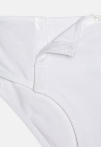 Witte katoenen slip met een zachte textuur, verstelbare banden en gestikte details bij de naden en de tailleband.