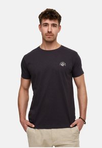 Schwarzes T-Shirt mit kurzen Ärmeln aus weichem Stoff, mit einem kleinen weißen Logo auf der linken Brustseite und einem Rundhalsausschnitt.