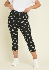 Svarta capri leggings med ett prydnadsmönster av prästkragar, tillverkade av ett stretchigt material, med en figurnära design och en midjehöjd som når till midjan.