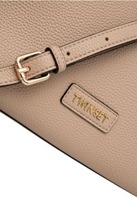 Borsa in pelle beige con texture, dotata di tracolla regolabile e fibbia dorata, caratterizzata da una placca con il logo "TWINSET" in oro.