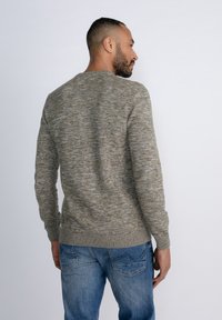 Grijze en groene gemêleerde gebreide trui met een ronde hals, ribbelmanchetten en onderkant. Draagcomfortabel over blauwe jeans met een gestructureerde afwerking.