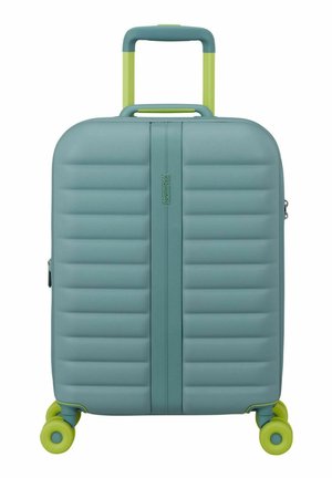 Maleta rígida azul verdosa con estrías horizontales, asa telescópica verde lima y cuatro ruedas giratorias verde lima.