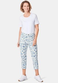 Lichtgewicht witte t-shirt gecombineerd met enkel-lange blauw-witte bloemenprint broeken, gedragen met witte sneakers. Eenvoudig ontwerp en casual pasvorm.