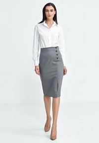 Szara spódnica ołówkowa z pionowymi paskami, rozporkiem po boku i pięcioma guzikami w talii; zestawiona z elegancką białą koszulą z guzikami.