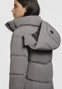 Hall puffer jope kõrge kraega ning eemaldatava kapuutsiga. Omab quiltitud osi ja taskut lukuga külgedel. Sile tekstuur.