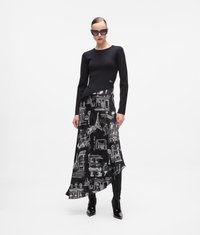 Top negru cu mâneci lungi asociat cu o fustă neagră ce are desene albe ale unor obiective turistice pariziene. Botine negre lucioase, până la glezne, completează ținuta.
