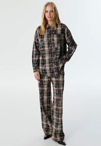 Braun und schwarz karierter Hemd- und Hosenanzug; zeichnet sich durch eine lockere Passform, einen Button-Down-Kragen und subtile Stickdetails aus. Strukturierter Stofffinish.