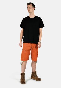 Schwarzes Baumwoll-T-Shirt, orange Cargo-Shorts mit Seitentaschen, beigen Akzenten, kombiniert mit braunen Schnürstiefeln. Minimalistisches Design.