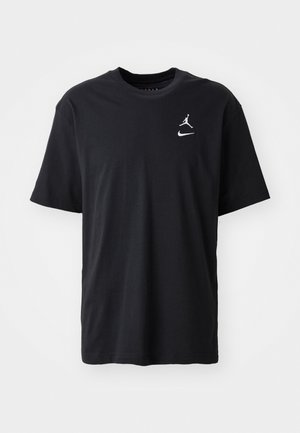 Črna bombažna majica s kratkimi rokavi, okroglim izrezom in belimi logotipi Jordan in Nike na levem prsnem košu. Gladka tekstura.