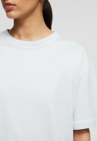 Hellblaue T-Shirt mit rundem Ausschnitt und überschnittenen Schultern. Weicher Baumwollstoff mit glatter Textur und ohne sichtbare Muster oder Akzente.