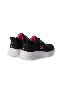 Zapatillas deportivas negras con forro interior rosa, suelas texturizadas blancas y logotipo "C" rosa en los laterales y en las lengüetas del talón.