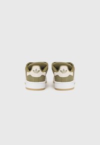 Baskets en daim vert avec semelle blanche, dotées d'un accent beige sur le talon et d'un logo signature. Texture lisse, design basse.