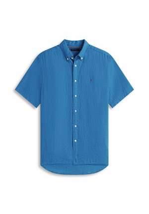 Chemise bleu à manches courtes avec boutons, col boutonné et petit logo sur la poitrine, présentée sur un fond blanc.