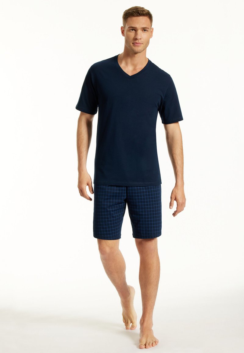 Navy-blaues V-Ausschnitt-T-Shirt kombiniert mit karierter Shorts in Dunkelblau, aus leichtem Material und mit lockerer Passform.