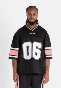Jersey deportivo negro de manga corta, presenta un gran "06" blanco en la parte frontal, rayas rosas y blancas en las mangas, con un cuello en V y un logo.