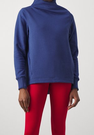 Sweatshirt en polaire bleu marine avec un col montant, des poignets côtelés et des coutures latérales, associé à des leggings rouges côtelés.