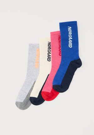 Quatre paires de chaussettes de sport en gris, crème, rose et bleu, chacune avec des bouts et talons contrastants et le nom de la marque inscrit sur le côté.