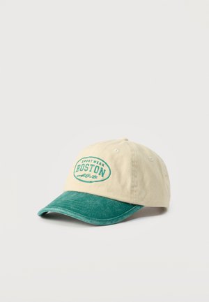 Béžová a zelená baseballová čiapka s výšivkou "Sport Wear Boston Athletic" na prednej strane, zobrazená na jednoduchom svetlom pozadí.