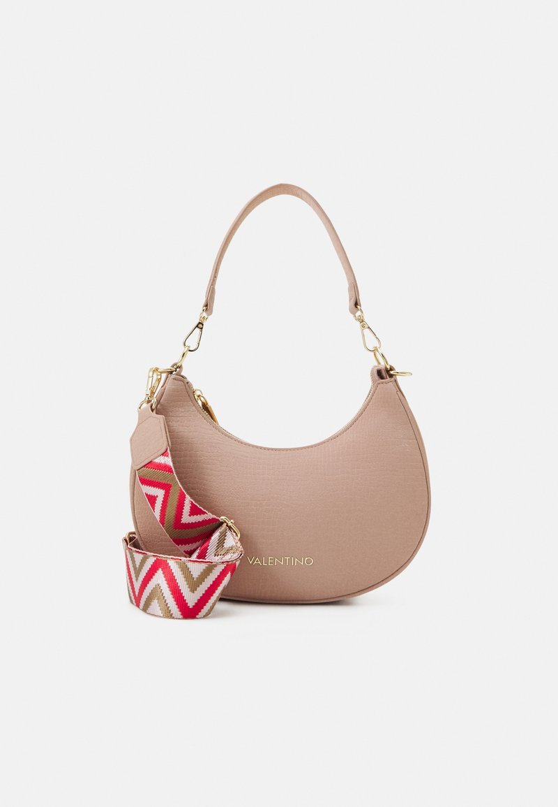 Tan textured shoulder bag with a curved shape, gold hardware, and a detachable patterned strap featuring pink, red, and beige zigzag designs.