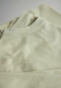 Komplekts ar trim gaiši zaļām kokvilnas T-kreklām ar apaļu kakla izgriezumu, īsām piedurknēm un redzamām šuvēm.