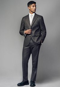 Braun kariertes Anzugjackett mit schlanker Passform, bestehend aus einem Ein-Knopf-Blazer, einem weißen Hemd und schwarzen Lederschuhen. Glattes Gewebe mit subtiler Textur.