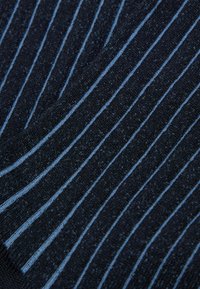 Marineblaue Strickware mit vertikalen hellblauen Streifen, die ein strukturiertes Muster mit unterschiedlichen Dicken und einem weichen Aussehen zeigt.