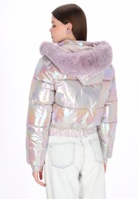 Perłowa kurtka puchowa z miękkim kapturze z liliowego sztucznego futra, elastycznym pasem i długimi rękawami, w zestawie z jasnymi jeansami.