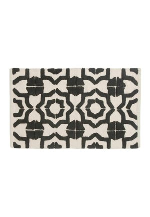Alfombra rectangular con fondo blanco y patrones geométricos abstractos negros en un diseño simétrico repetitivo.