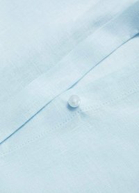 Camicia di lino blu chiaro con una texture liscia, dotata di un unico bottone bianco e cuciture pulite lungo la pattina.