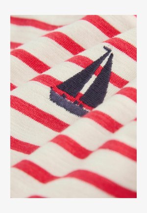 Tessuto a righe rosse e bianche con dettaglio ricamato di una barca a vela blu navy. Texture morbida, principalmente in cotone, piegato ordinatamente.