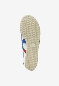 Suole delle scarpe realizzate in un materiale gommoso crema con una texture a triangoli. Accenti blu e rossi sui lati con una base bianca.