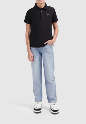 Zwarte polo met korte mouwen, drie knopen en een logo, gecombineerd met lichtblauwe rechte jeans en zwart-witte sneakers.