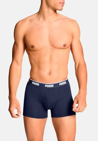 Blaue Boxershorts mit einem weißen Bund, der das Puma-Logo zeigt. Hergestellt aus dehnbarem Stoff, bieten sie eine figurschmeichelnde Passform für Komfort.