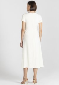 Biała, dopasowana sukienka z krótkimi rękawami i okrągłym dekoltem. Sięga do połowy łydki, z zamkiem błyskawicznym z tyłu i gładką fakturą.