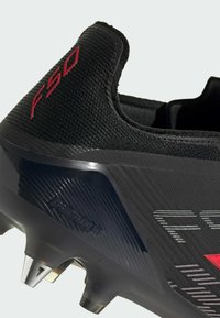 Μαύρο αθλητικό παπούτσι με κόκκινο κείμενο "F50", μεταλλικά σταθερά καρφιά στη σόλα και υφασμένη επάνω επιφάνεια με τη σήμανση "SPRINTFRAME".