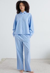 Ljusblå randig pyjamas med mjukt tyg, som har en skjortkrage och knappar i toppen samt avslappnade byxor med rak passform.
